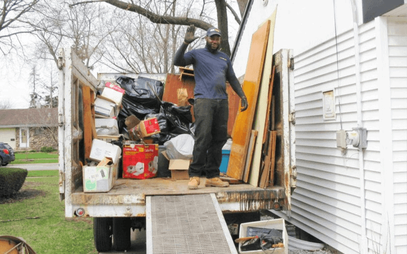 Worker loading items into a junk removal truck