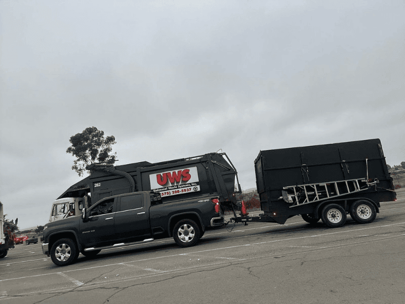 Blue truck towing large black utility trailer on road