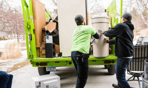 Workers loading appliance into green moving truck