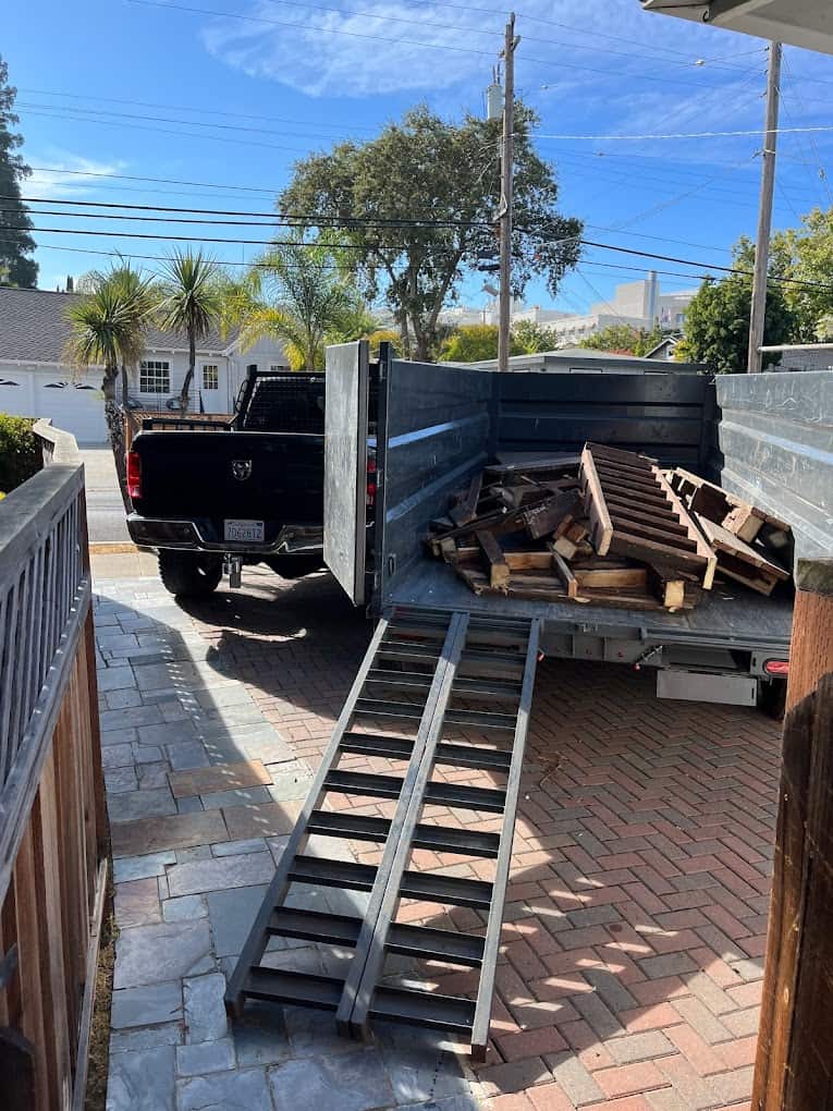 Truck loaded with wood planks in sunny driveway.