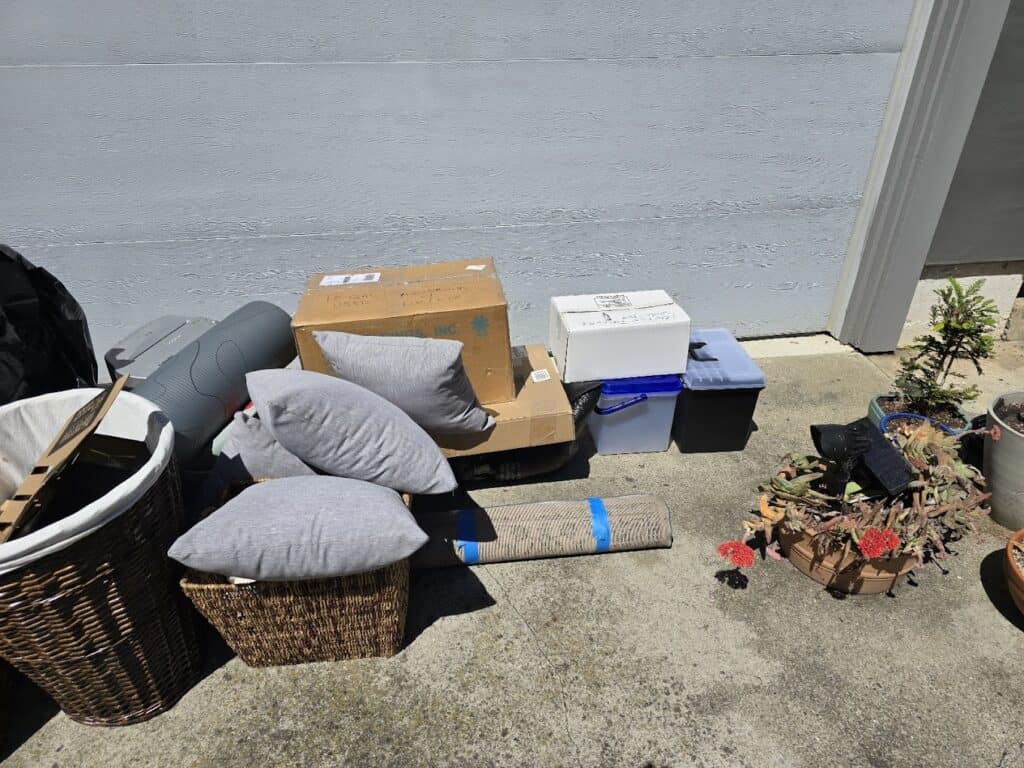 Assorted items and boxes discarded on sunny sidewalk