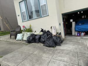 Garbage bags piled outside a house with open garage
