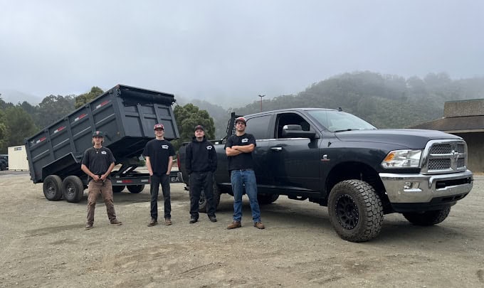 Four workers posing with truck and open dump trailer