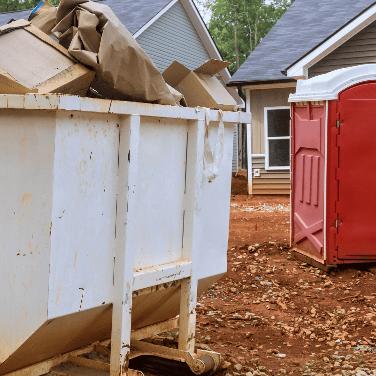 Overflowing dumpster at construction site with portable toilet