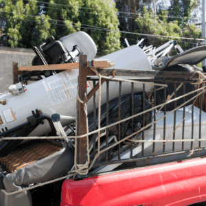 Overloaded truck carrying various appliances and debris