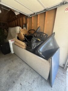 Cluttered garage filled with discarded items and furniture