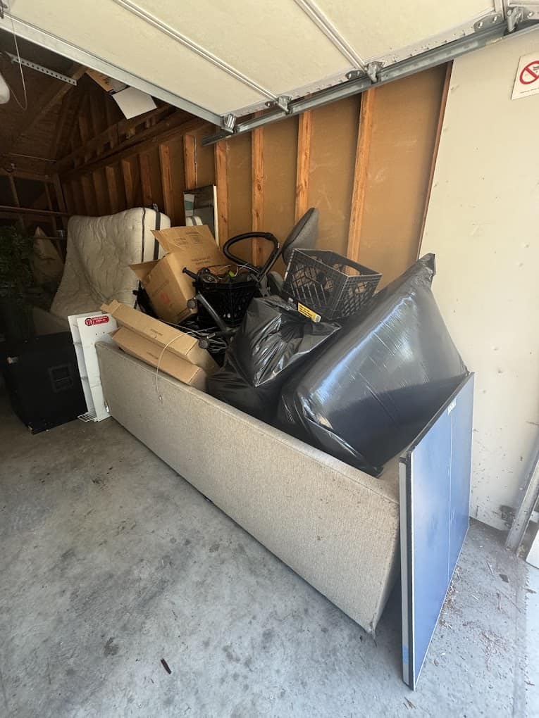 Cluttered garage filled with discarded items and furniture