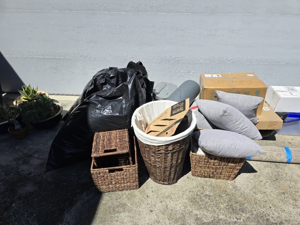 Various discarded items and boxes beside a gray wall